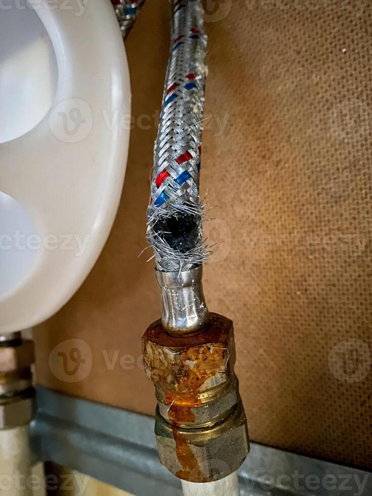 During a detailed examination, a water hose reveals a significant hole, indicating potential wear or aging damage. Its crucial to promptly address this issue to prevent further problems photo