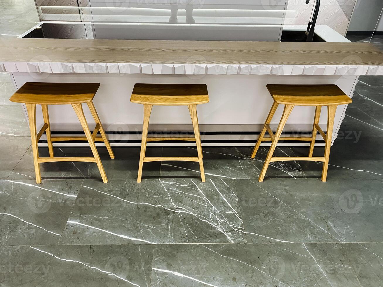 In the space before a kitchen island, three wooden stools are neatly arranged, creating a welcoming and functional area perfect for casual dining or conversations over coffee photo
