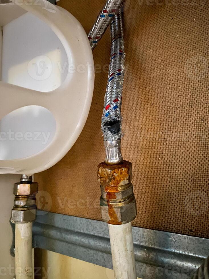 A closeup of a rusty pipe near the sink in the bathroom highlights industrial and organic design elements, blending metal, plumbing, and natural components for a unique aesthetic photo