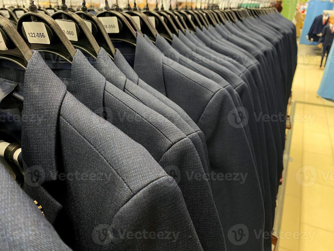 In a beautifully designed store display, elegant blue suits hang on neatly arranged racks, showcasing the latest collection for customers to browse and enjoy their shopping experience photo