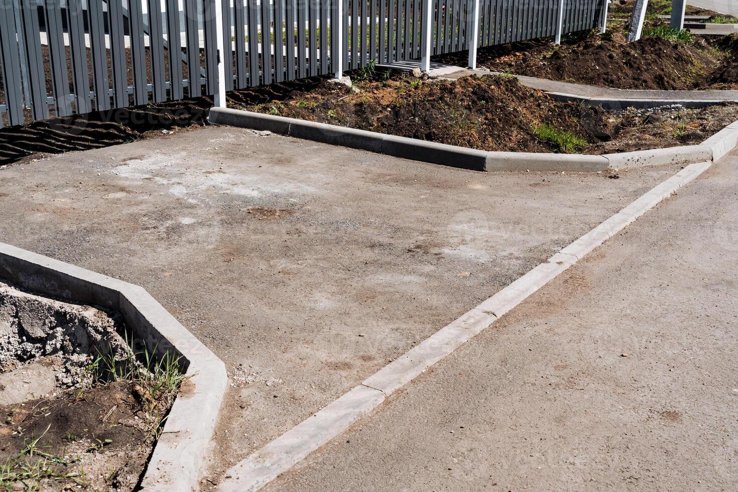 Infrastructure project underway constructing concrete walkway next to fence photo