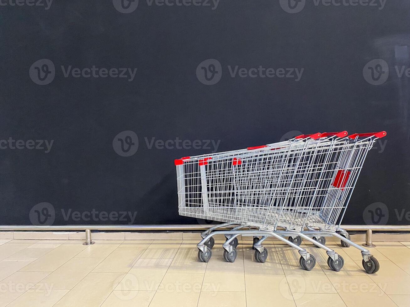 The image shows empty shopping carts against a black wall, presenting a minimalist view that effectively captures the essence of a retail environment photo