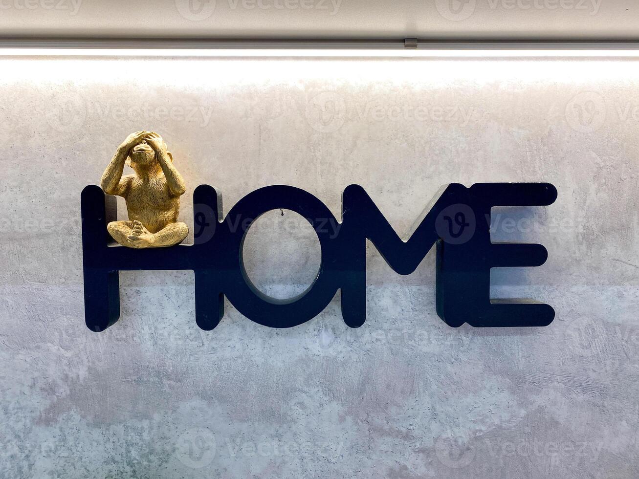 An intriguing monkey statue, whimsically placed on the word home, adds a delightful and charming touch to the overall decor and atmosphere of the entire space, creating warmth and joy photo