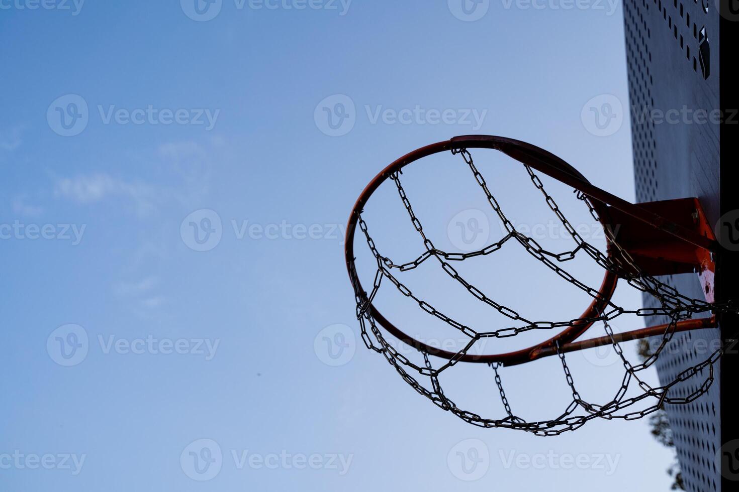 A basketball hoop is prominently displayed against the backdrop of a bright blue sky, creating a vibrant scene that captures the essence of outdoor sports and leisure activities photo
