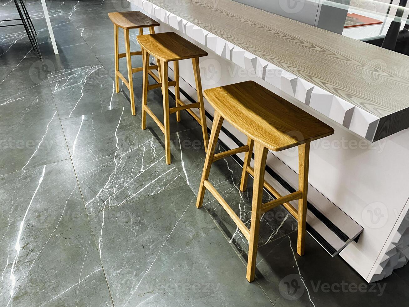 Three beautiful and sturdy wooden bar stools are placed next to a counter, creating a cozy and inviting atmosphere for friends and family to gather and enjoy each others company photo