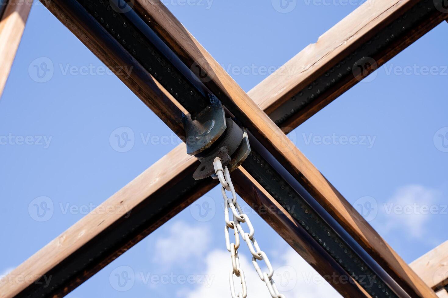 A sturdy chain is elegantly hanging down from the ceiling of a beautifully crafted wooden structure, adding both functionality and aesthetic appeal to the overall architecture photo