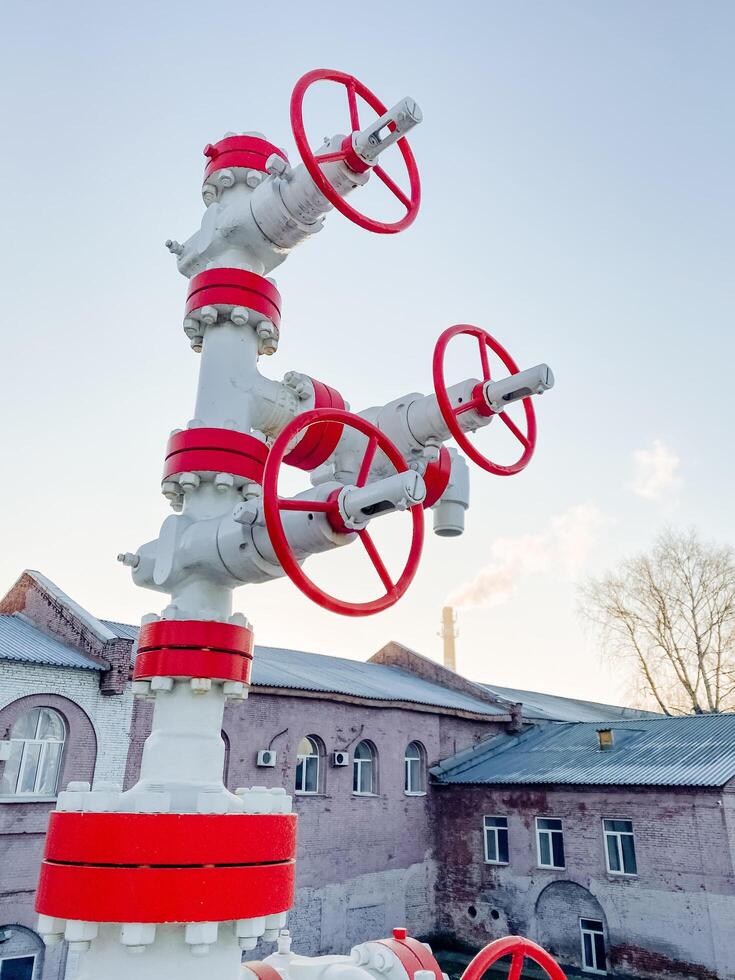 In front of a large building, there is a long white pipe that features shiny red wheels attached to it, creating an interesting sight against the backdrop of the structure photo