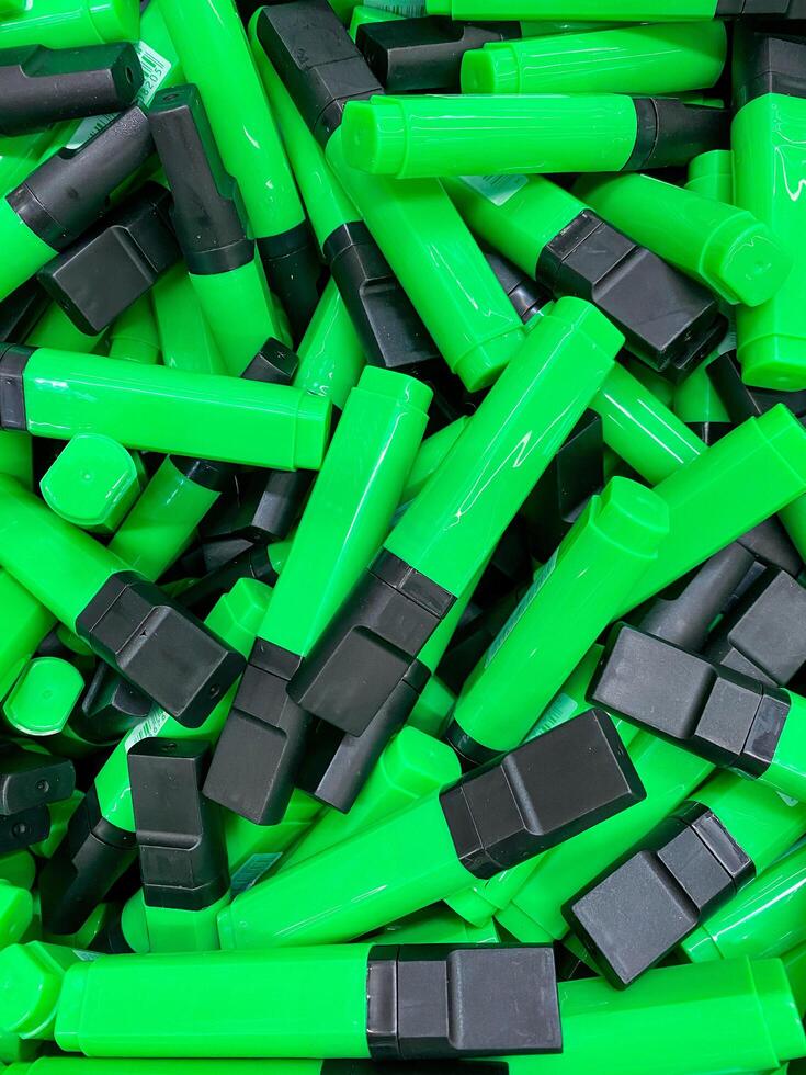 A neatly organized stack of green and black highlighters creates a vibrant contrast that adds an eyecatching pop of color to enhance the aesthetic of any workspace or desk area photo