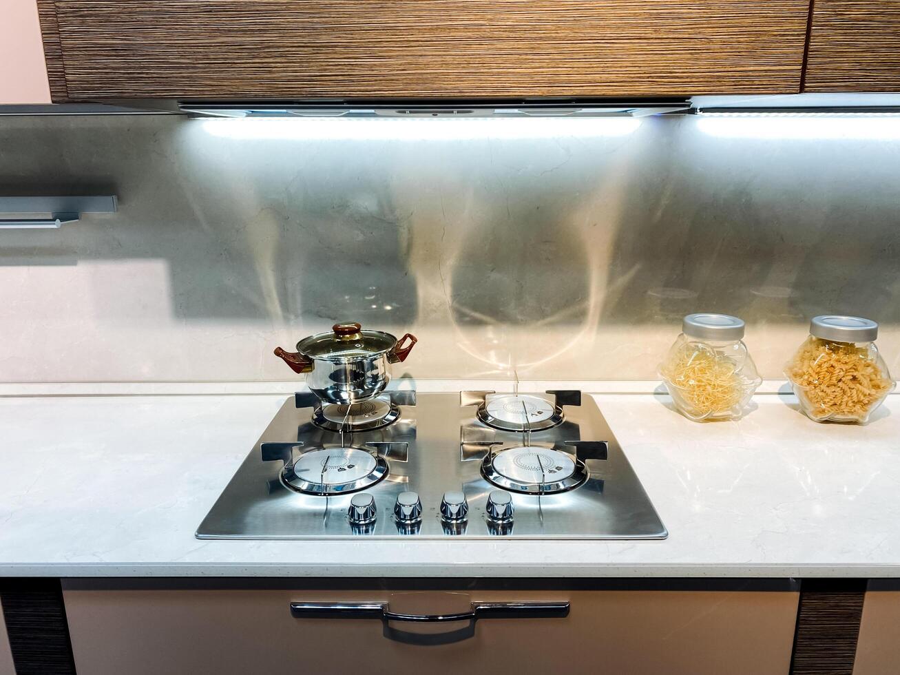 Imagine a beautifully designed kitchen that features a gas stove top oven, complemented by jars filled with various types of pasta, proudly displayed on the countertop for quick access photo
