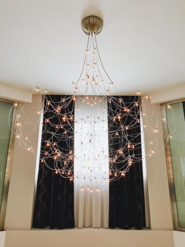A large and beautifully designed chandelier is gracefully hanging from the ceiling directly above a window, adding a touch of elegance and style to the rooms overall decor photo