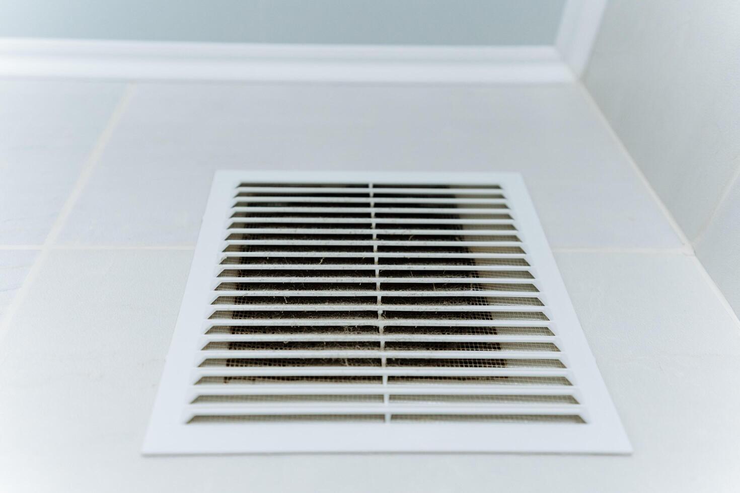 In a room, there is a white air vent installed on a white wall, creating a seamless look that blends with the surroundings, providing efficient air circulation throughout the space photo