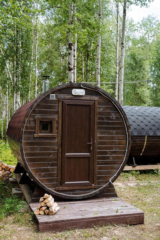In a magnificent and magical forest, a uniquely crafted wooden barrel stands out with an inviting door that captivates the attention of all passersby amidst the lush greenery surrounding it photo