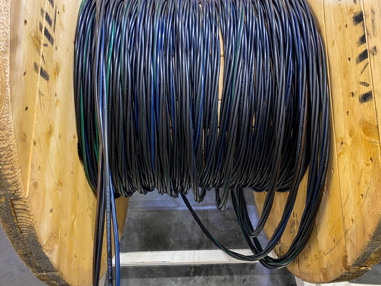 A spool of various wires is currently resting on a sturdy wooden spool, creating an interesting visual contrast between the materials and showcasing their respective functionalities photo