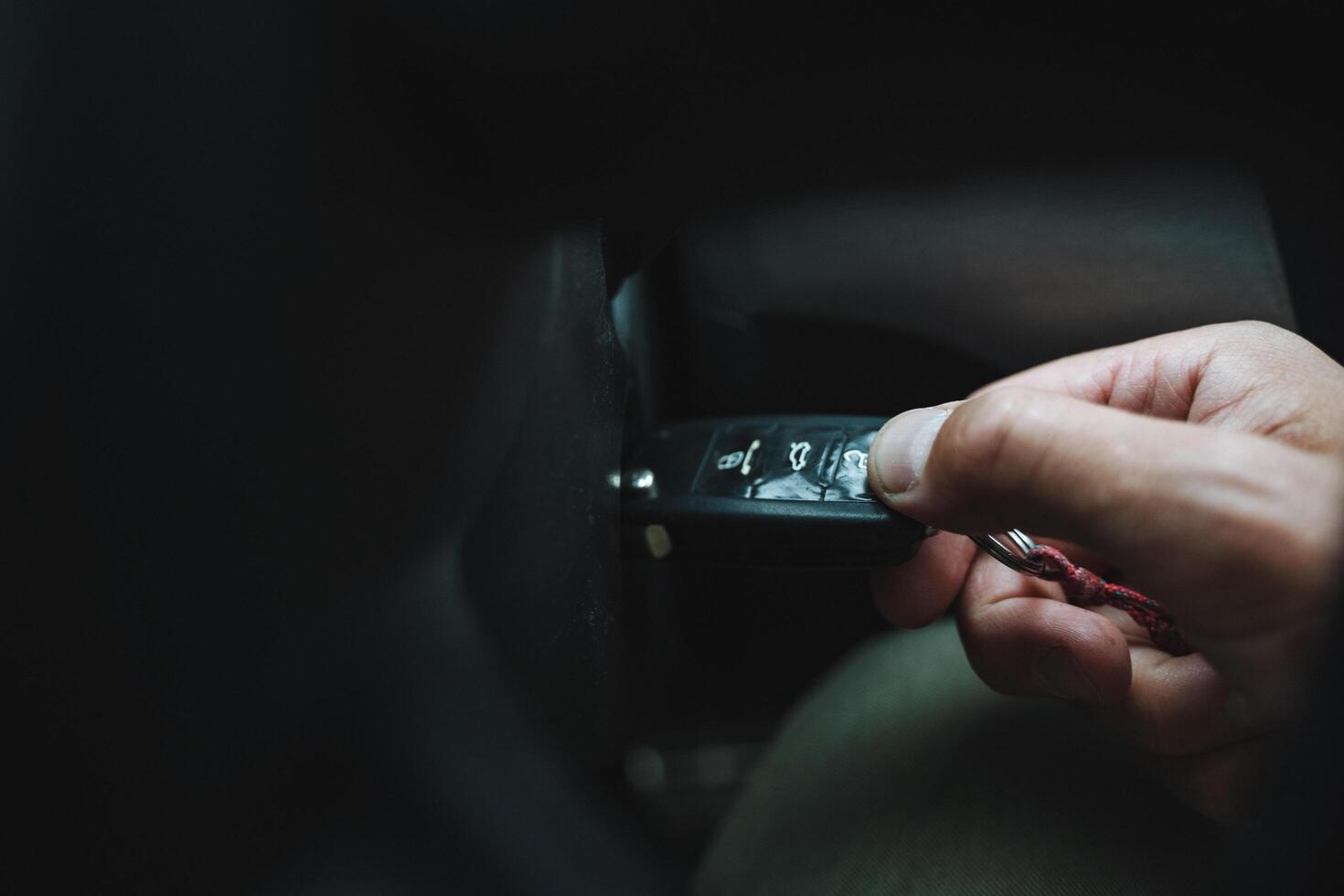 In the picture, a hand holds a car key with a purposeful gesture. Keywords are Gesture, Thumb, Event, Nail, Darkness, Glass, Wrist, Auto part, Fashion accessory, and Jewellery photo