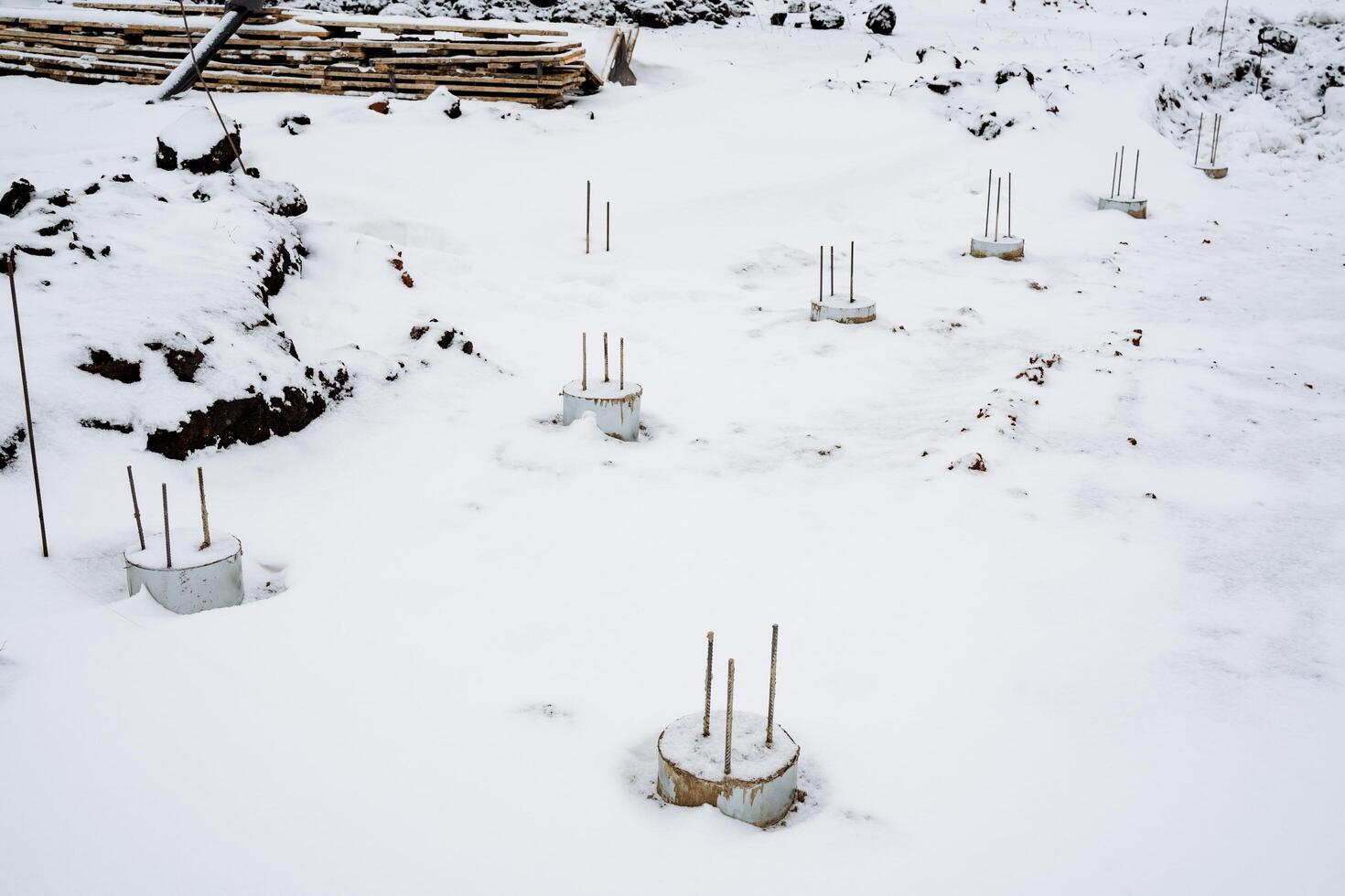 In a vast, snowy field covered in a thick blanket of white, there are numerous concrete pillars that stand tall amidst the snow, creating a striking contrast with the winter landscape photo
