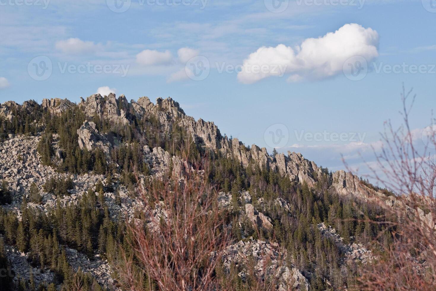 A natural landscape featuring a majestic mountain, trees, and clouds photo