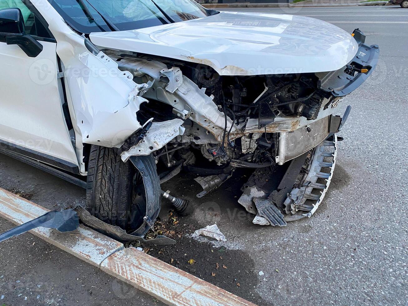 On the side of the road, a white car with a damaged front end displays signs of wear and tear, indicating it has been in an accident. The vehicle is showing visible damage photo