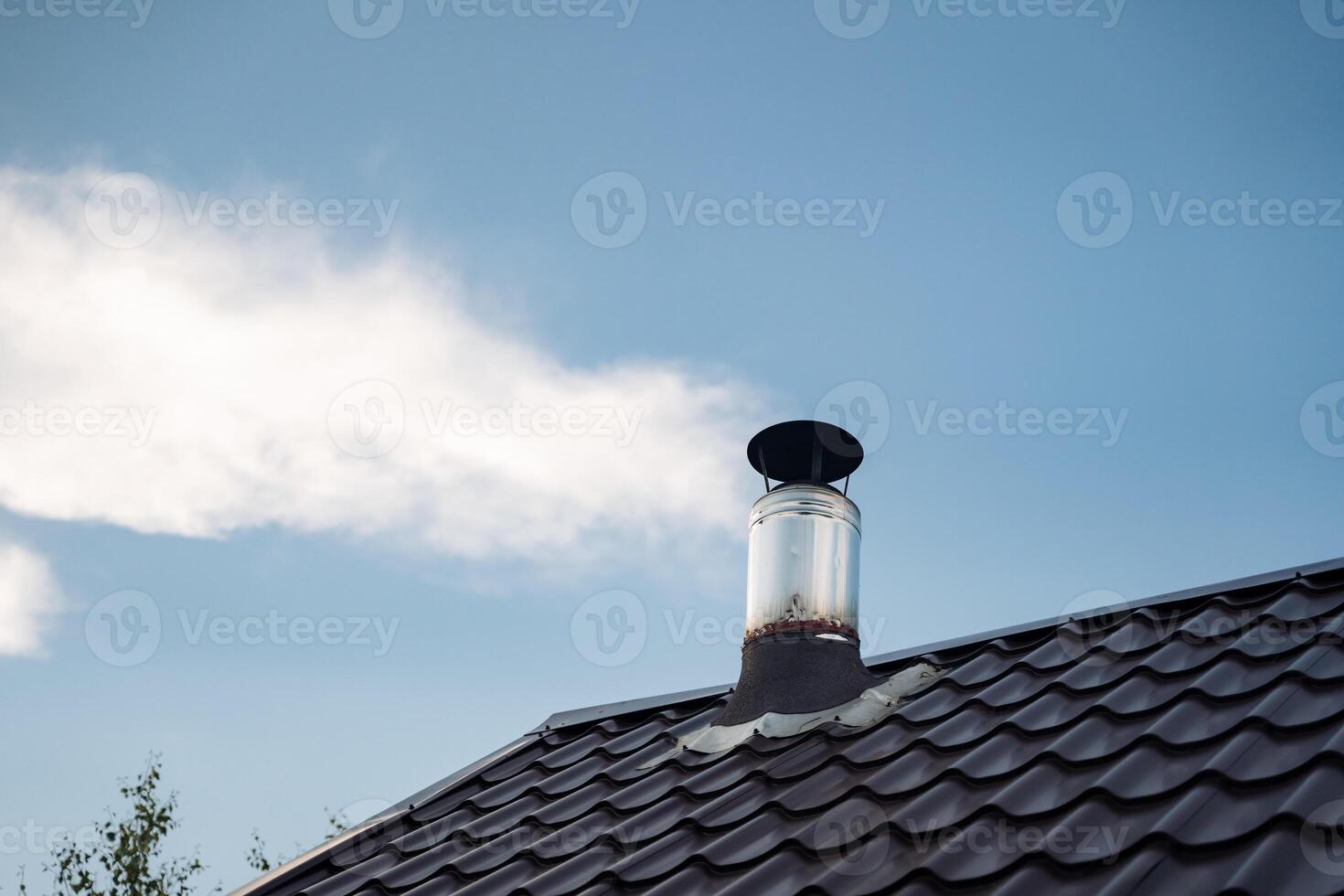 The picture showcases a structure with a chimney releasing smoke into the air against a cloudy sky, showcasing a cohesive mix of architecture, engineering, and natural elements photo