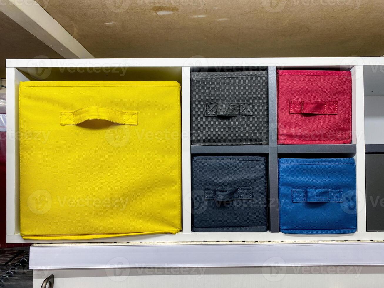 On a wellorganized shelf, there lies a bright yellow box positioned right in the center, standing out against the background, making it quite the eyecatching sight among other items photo