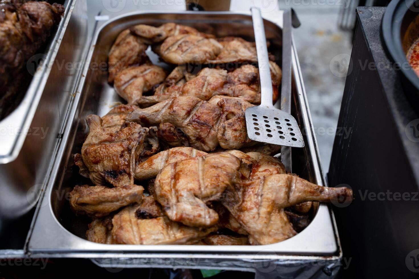 A beautifully arranged tray overflowing with succulent grilled chicken pieces and a spatula beside it, ready to serve a delightful meal. Enjoy the amazing taste that satisfies your hunger photo