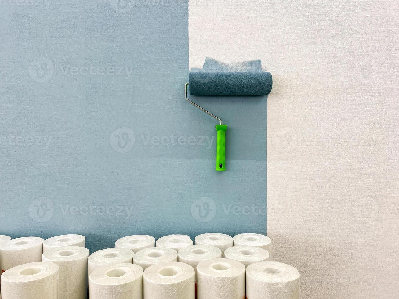 In this room, a roll of toilet paper is placed beside a paint roller against the wall, creating an interesting contrast between these two distinct yet oddly paired items photo