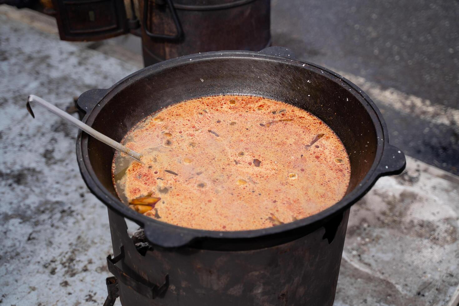A Mouthwatering Delicious Stew is Cooking in a Large Pot Over an Open Fire, Filling the Air with Aroma photo