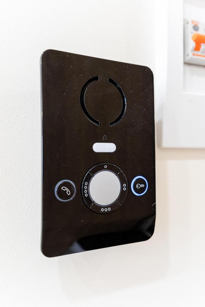 A black and white remote control is currently hanging on a pristine white wall, adding an interesting contrast to the overall decor of the space it is in, creating visual appeal photo
