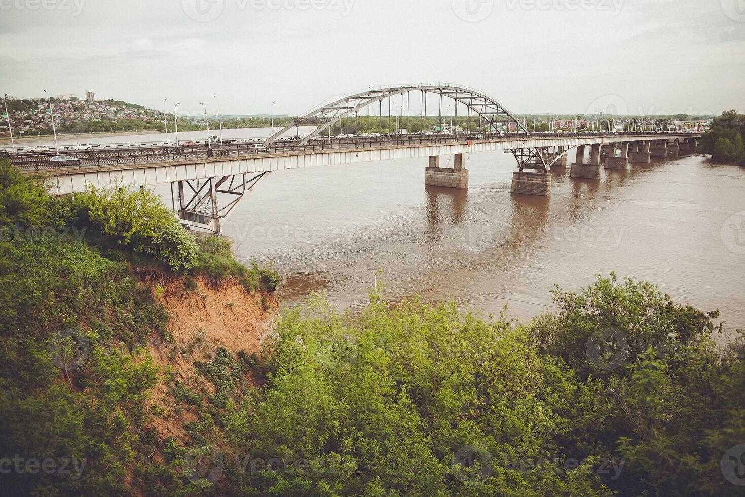 Arch bridge over water with city skyline in the background photo