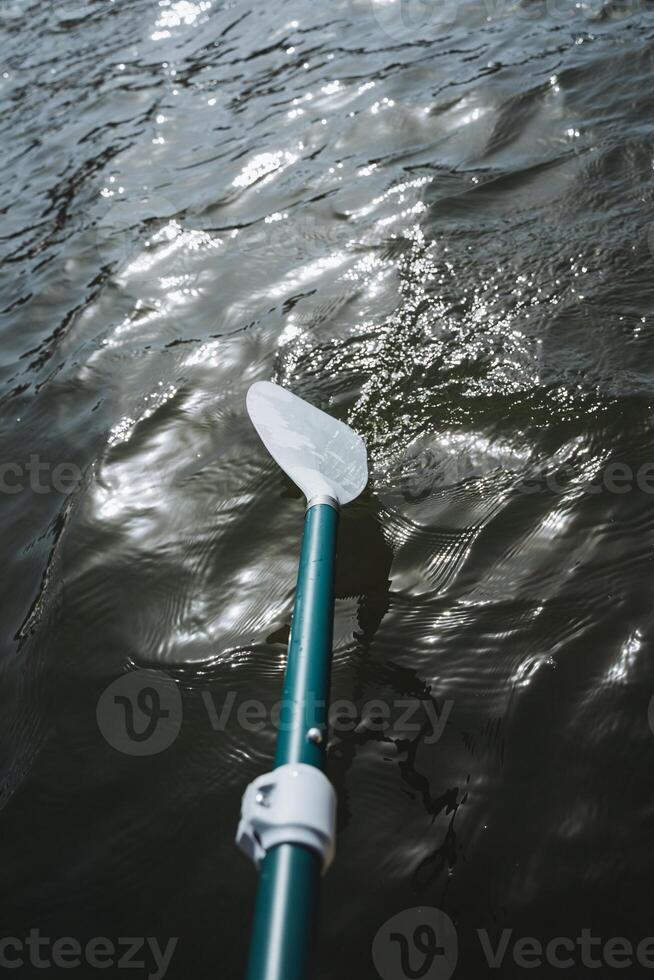 Close up of a paddle slicing through the liquid surface of a lake photo