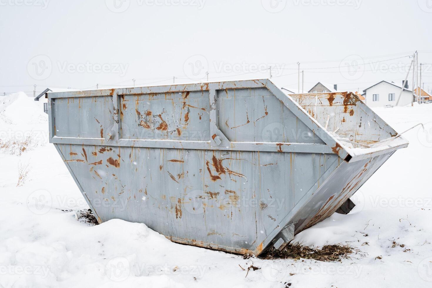 Amidst the biting chill of winter, a rusty old dumpster rests solitary in the thick white blanket of snow, highlighting its longneglected and forgotten condition in this frosty landscape photo