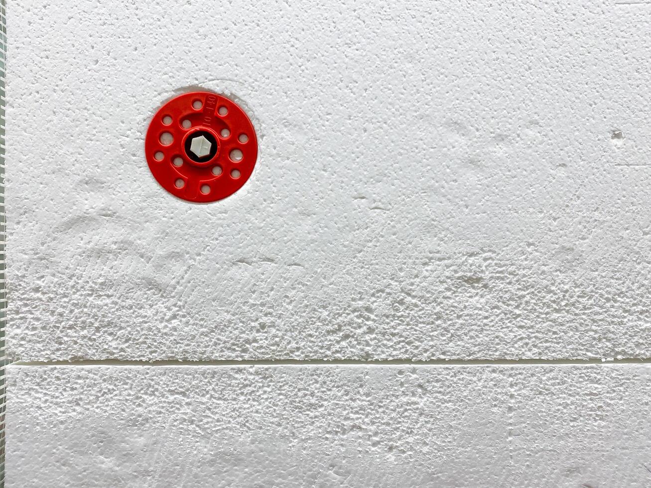 CloseUp of a Red Circular Object on a Textured White Surface with Subtle Patterns photo