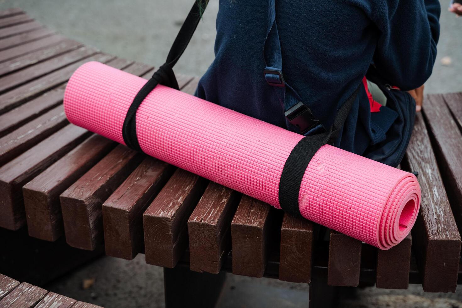 A person is doing fitness and relaxation exercises on a wooden bench outdoors with a pink yoga mat. The setting promotes health, wellness, mindfulness, and flexibility photo