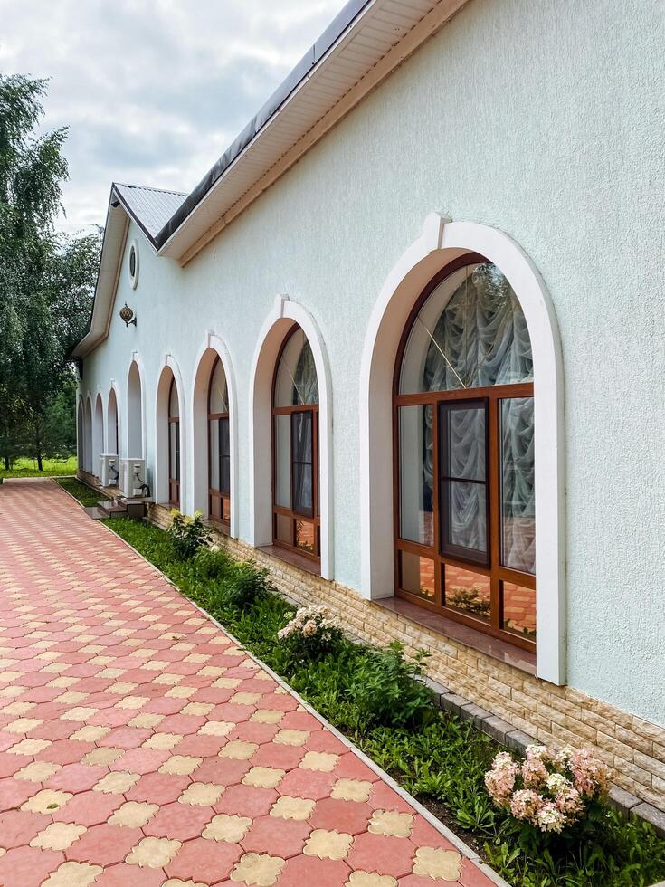 A stunning white building with elegant arched windows is complemented by a charming brick walkway leading to its grand entrance, captivating all who pass by and leaving a lasting impression photo