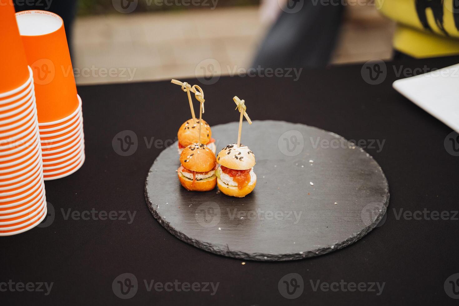 An elegant black plate on a beautifully set table holds three delightful appetizers, inviting you to savor their enticing flavors and intriguing textures, perfect for sharing photo