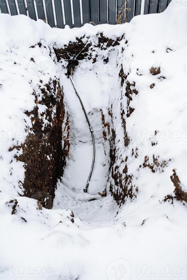 There is a noticeable hole in the snow with a thin wire protruding out of it, creating an interesting visual in the winter landscape, suggesting potential geological activity in the area photo