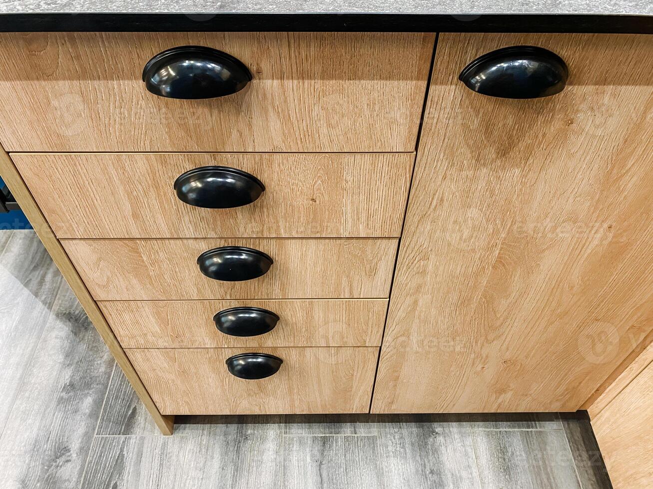 In this visually striking image, one can see a closeup of an exquisitely crafted wooden cabinet featuring stylish black handles that greatly enhance its overall sleek and elegant design photo