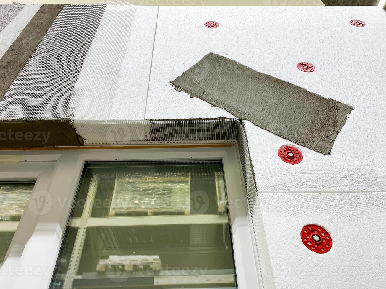 This is a detailed closeup view that showcases the application process of exterior insulation on a building at a busy construction site, highlighting craftsmanship photo