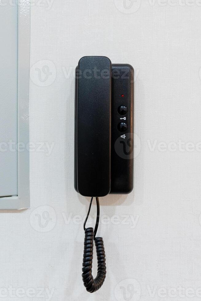 A classic black telephone against a bright white wall creates a striking contrast, enhancing the rooms decor and making it more inviting and visually pleasing to those who enter photo