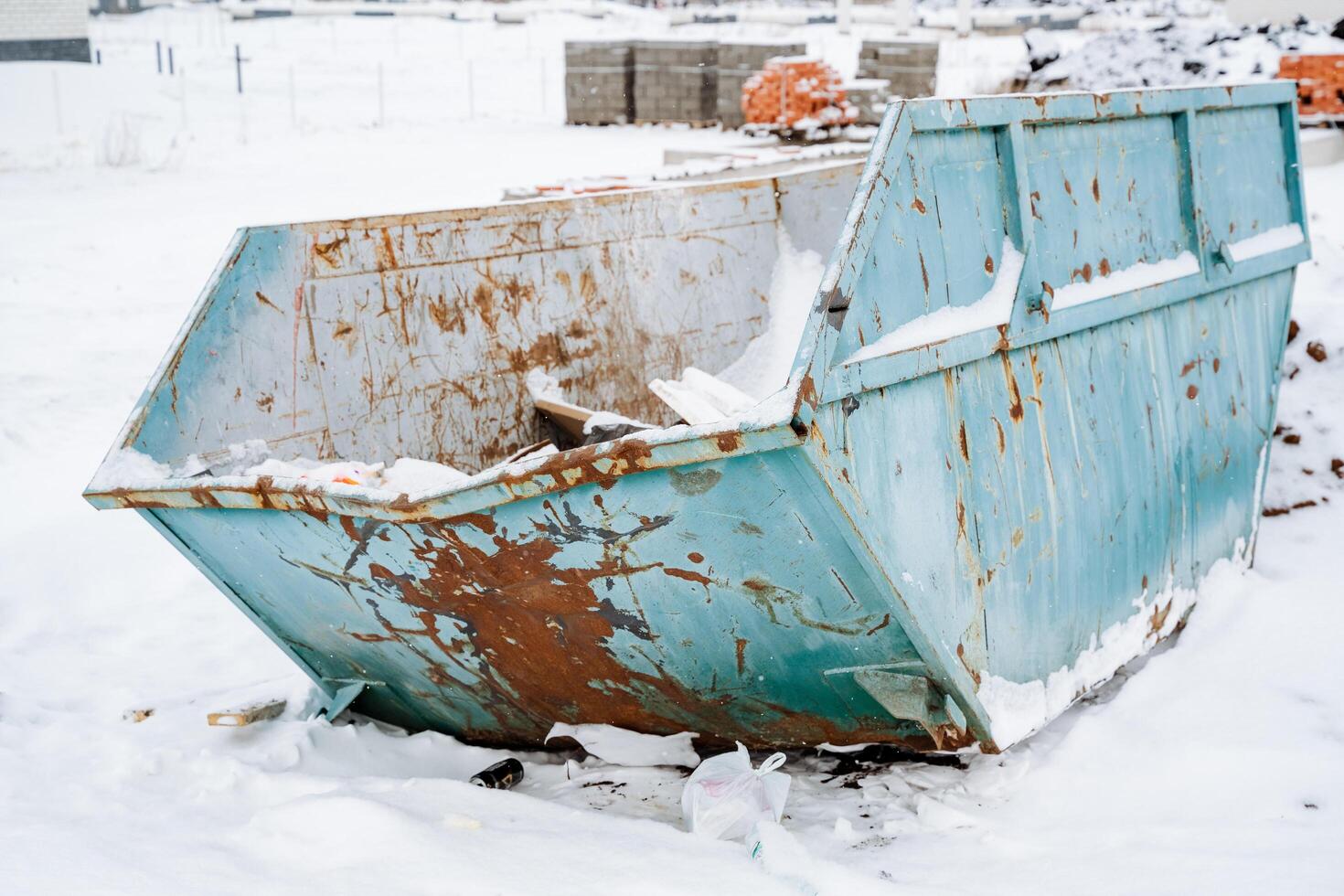 An old, rusty dumpster sits alone in a snowy landscape, contrasting with the white surroundings, and prompting thoughts on environmental issues and waste management photo