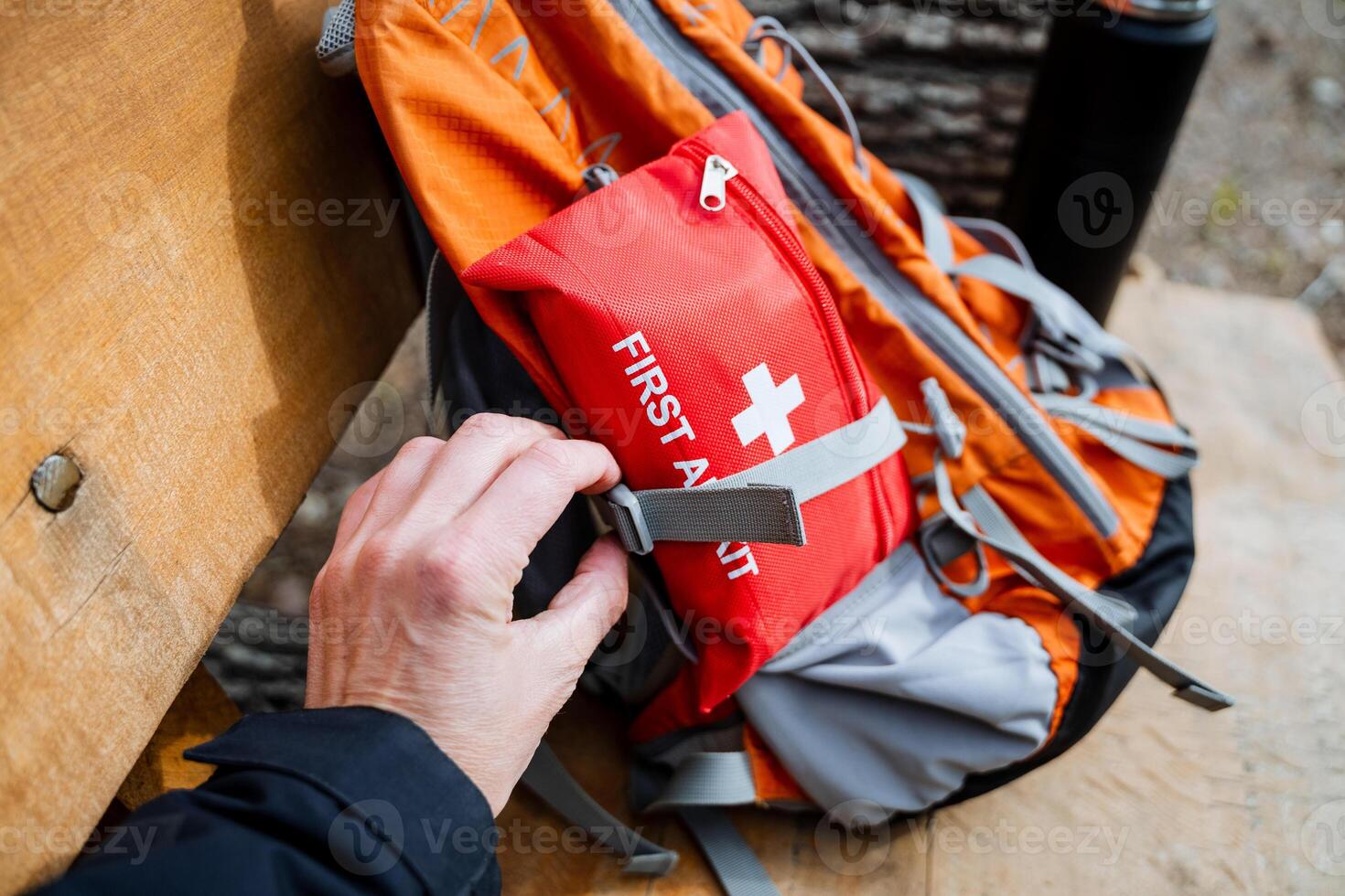 A person is stowing a first aid kit in a backpack photo