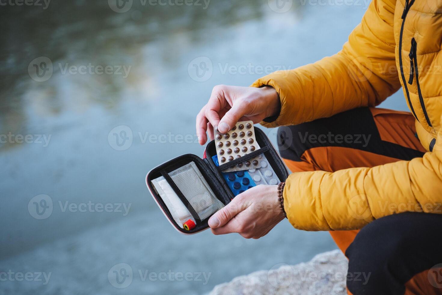 Pills in a first-aid kit, human hands holding an open first aid kit with medicines, first aid to a hiker on a hike, anti-nausea pills. photo