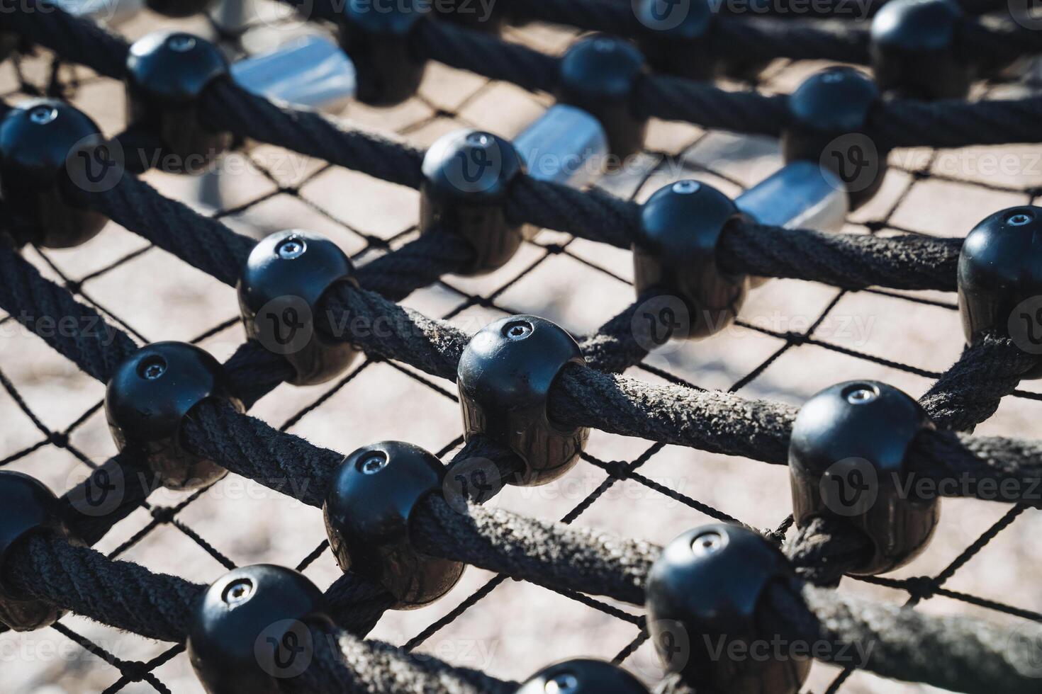 A detailed closeup view capturing a vibrant playground climbing net, featuring robust black ropes and colorful plastic nodes for fun photo
