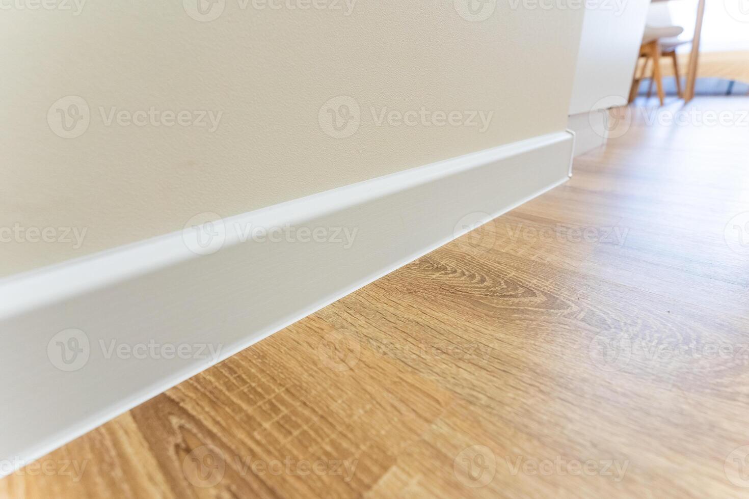 This is a detailed closeup view of a beautifully finished wooden floor which features a pristine white skirting board, highlighting the elegant contrast between the two elements photo
