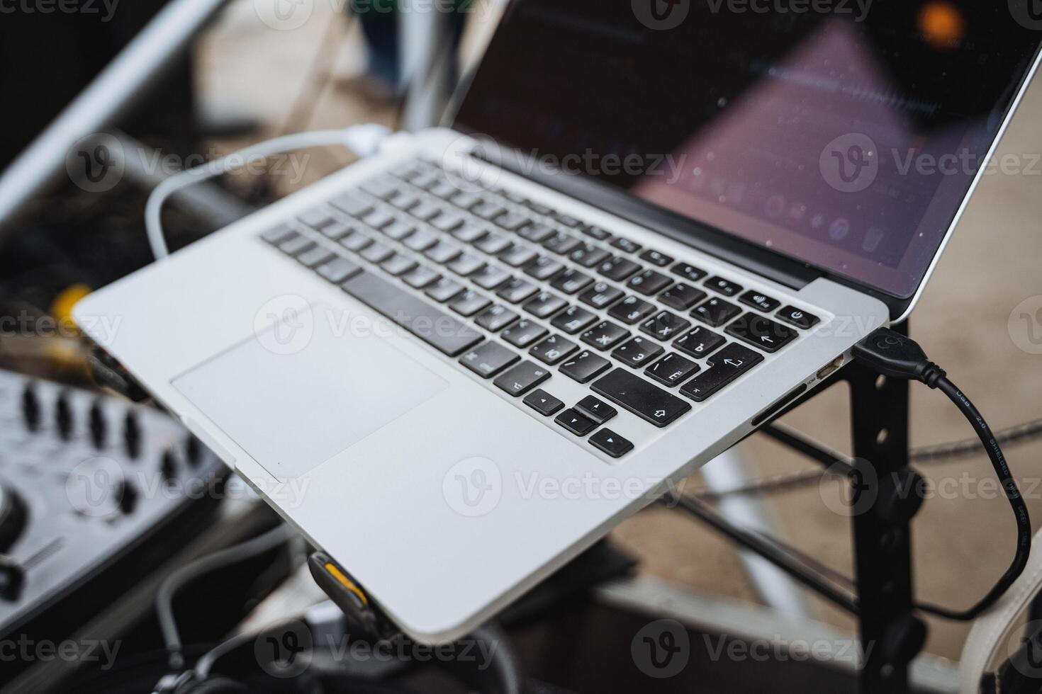 A laptop computer is currently positioned atop a microphone stand, showcasing an interesting setup for either a presentation or a recording session, blending technology and creativity photo