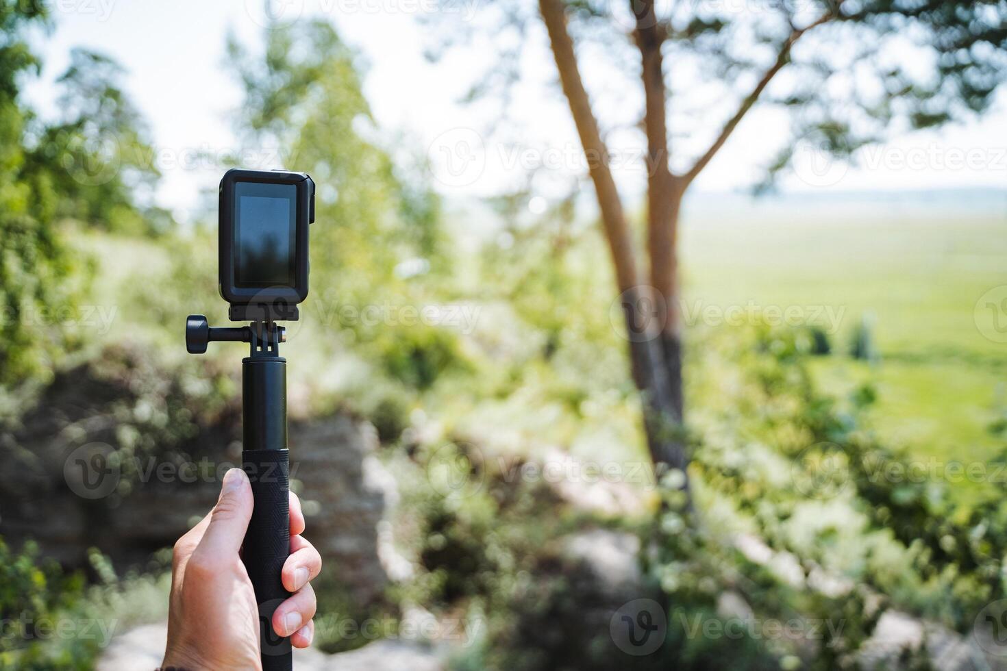 A person is using a gimbal stabilizer to hold an action camera in the scenic outdoors. The setting is perfect for capturing nature and wildlife with modern technology photo
