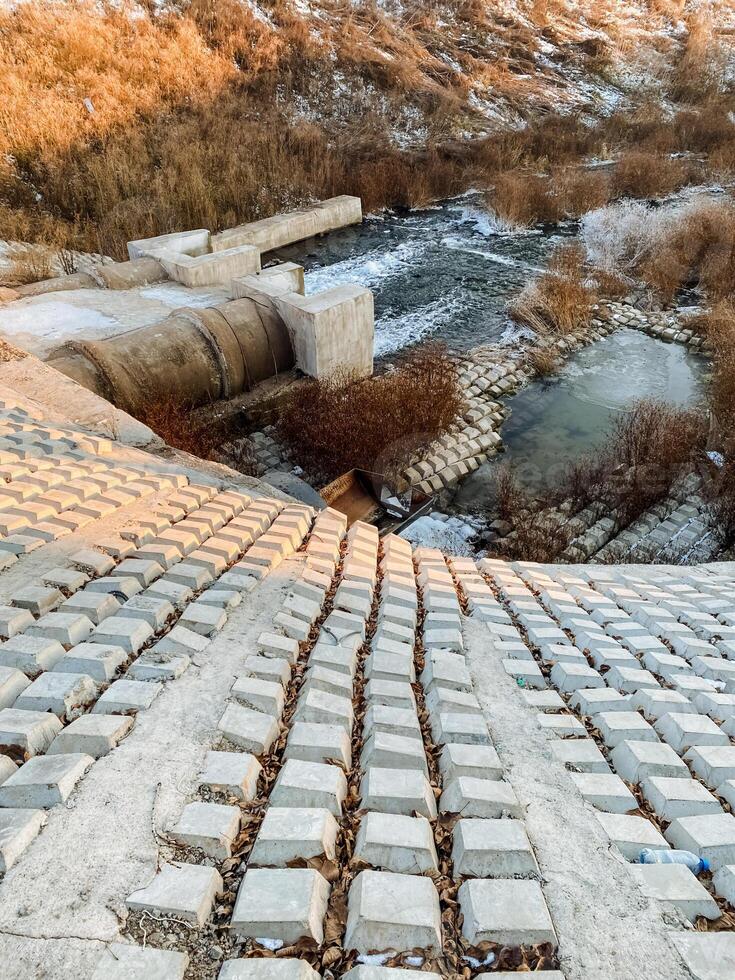A beautifully designed brick walkway that seamlessly leads to a serene river nestled within the stunning mountains in the distance, presenting a scenic view of natures splendor photo