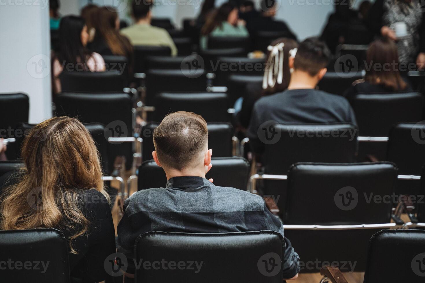 Crowd sitting in chairs, sharing the event in a lecture hall photo