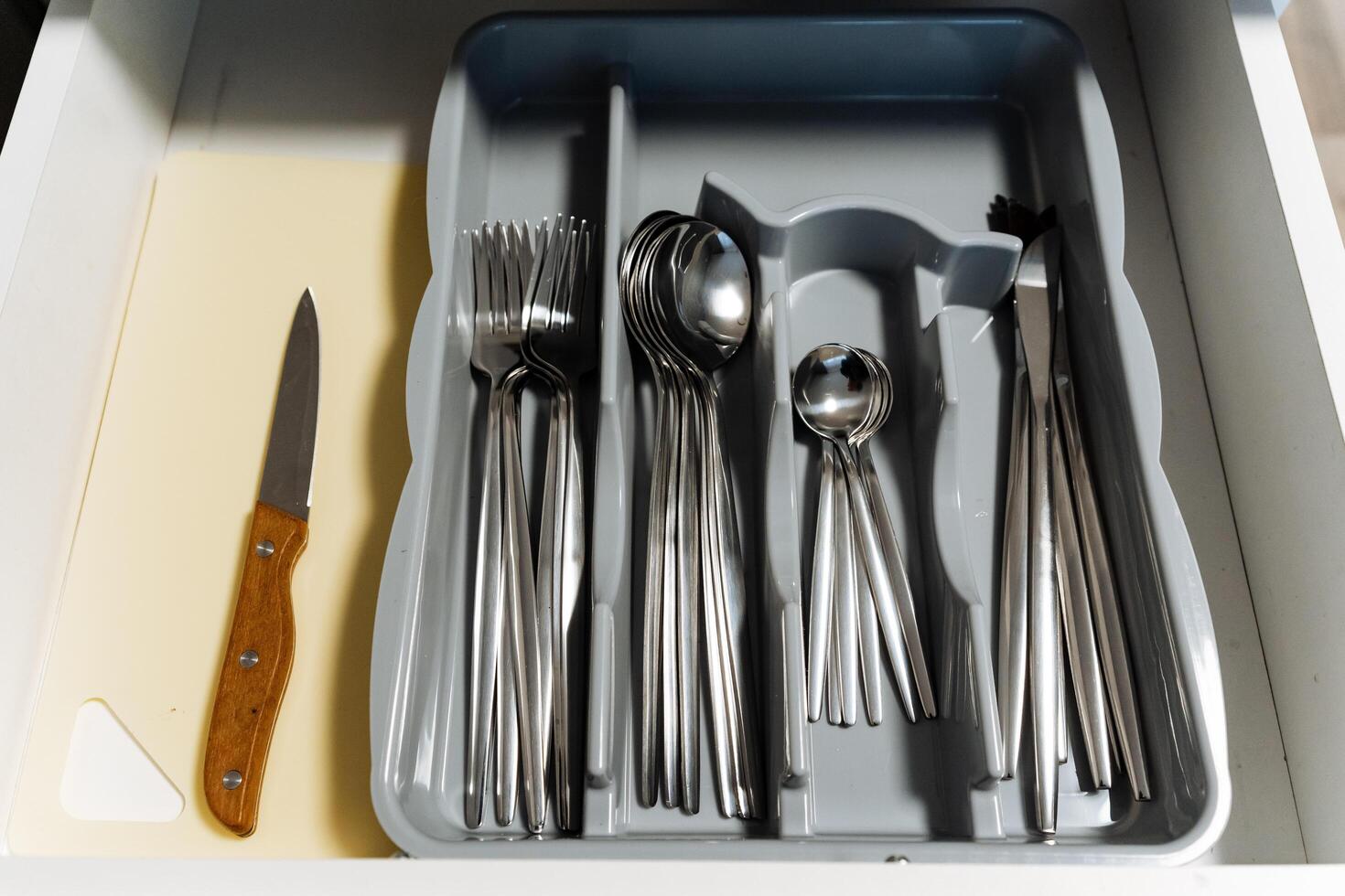A drawer that is filled with various pieces of silverware, including an assortment of spoons, forks, and knives, each serving a specific purpose in the kitchen or dining area photo