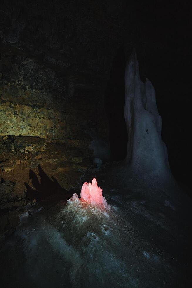Within the depths of a mysterious cave, a captivating pink crystal is illuminating the surrounding darkness, creating a magical atmosphere that enchants all who venture near it photo