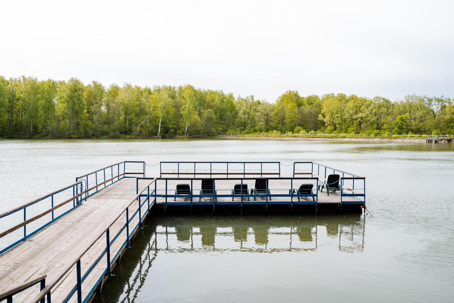 Enjoy the tranquility of a serene lakeside pier surrounded by the beauty of the forest, perfect for relaxation and fishing in a peaceful and picturesque environment photo
